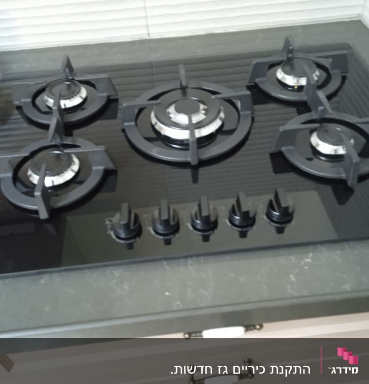 כיריים גז שחורות עם חמישה מבערים וכפתורי שליטה
